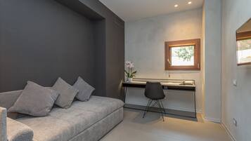 Un salon moderne avec un canapé gris, un petit bureau et une chaise.