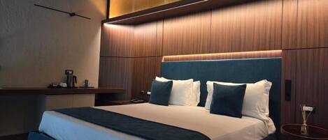Ein modernes Hotelzimmer mit einem großen Bett, einem Nachttisch und einem kleinen Beistelltisch.
