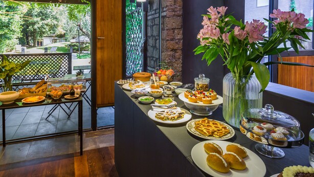 A buffet table with various food items and a vase of flowers. - Fauno Urban Resort (Rome)