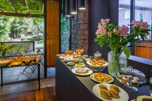 A buffet table with various food items and a vase of flowers. - Fauno Urban Resort (Rome)