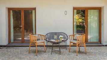 Un patio con una mesa, dos sillas, un ventanal y vistas a zonas verdes.