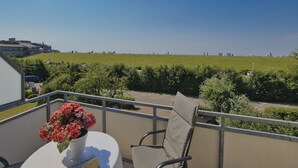A balcony with a table, chair, and a vase of flowers. - N19K (BC.a5) - Stranddomicil Steiner (Büsum)