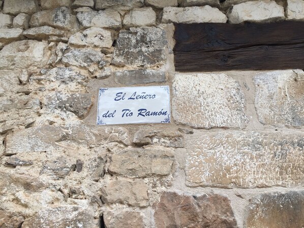 A stone wall with a sign reading "El Leno del Tio Ramón".