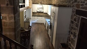 Una cocina rústica con paredes de piedra, vigas de madera y una lámpara colgante.