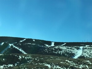 A mountainous landscape with snow patches and a clear blue sky.