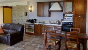 Una cocina compacta con armarios de madera, un microondas integrado y una estufa a gas.