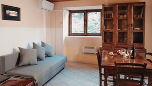 Une pièce comprenant un canapé, une table à manger, un meuble en bois et une fenêtre donnant sur un paysage agréable.