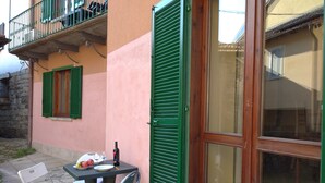 Une petite terrasse extérieure avec une table, des chaises et une bouteille de vin.