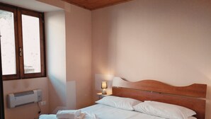 Une chambre à coucher avec une tête de lit en bois, une lampe de chevet et des serviettes soigneusement pliées sur le lit.