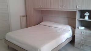A bedroom with a bed, a wardrobe, and a nightstand.