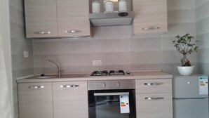A modern kitchen with stainless steel appliances, a built-in oven, a sink, and a potted plant.