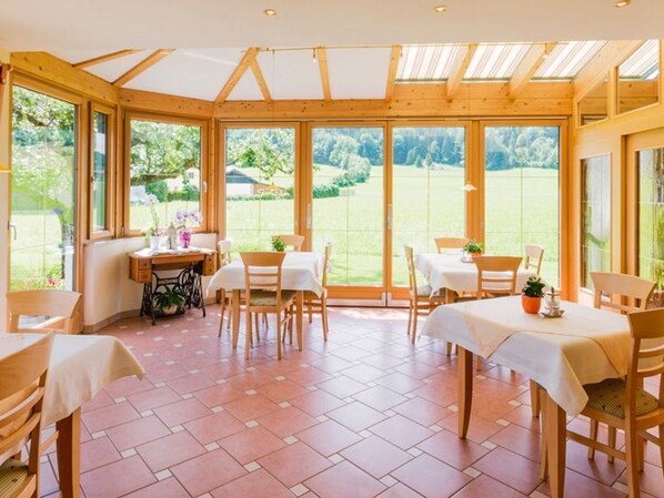 A conservatory with wooden beams, large windows, and a tiled floor.