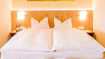 A double bed with white linens, two bedside tables with lamps, and a framed picture above the bed.