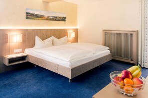 Un dormitorio con una cama de madera, lámparas de noche, una mesita de noche, un radiador y un frutero sobre una mesa.