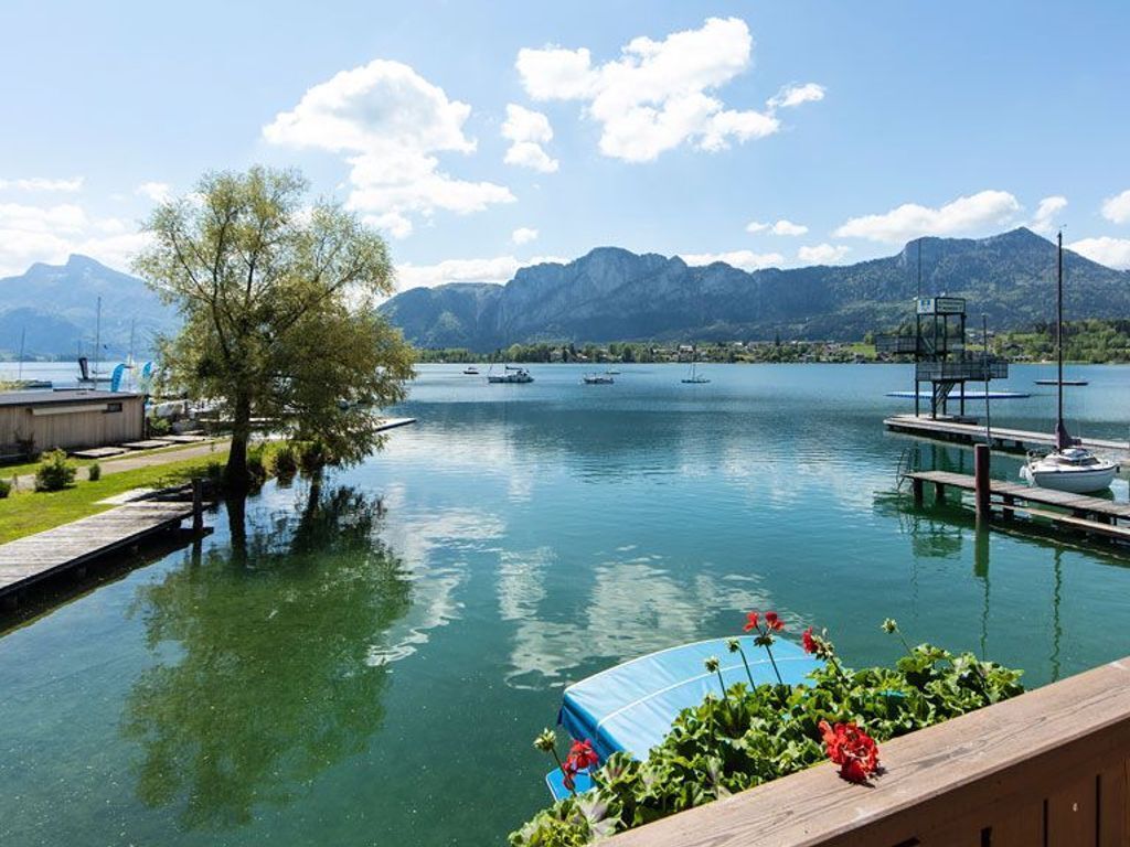 Une vue sur le lac, avec des bateaux, un quai et des montagnes en arrière-plan.