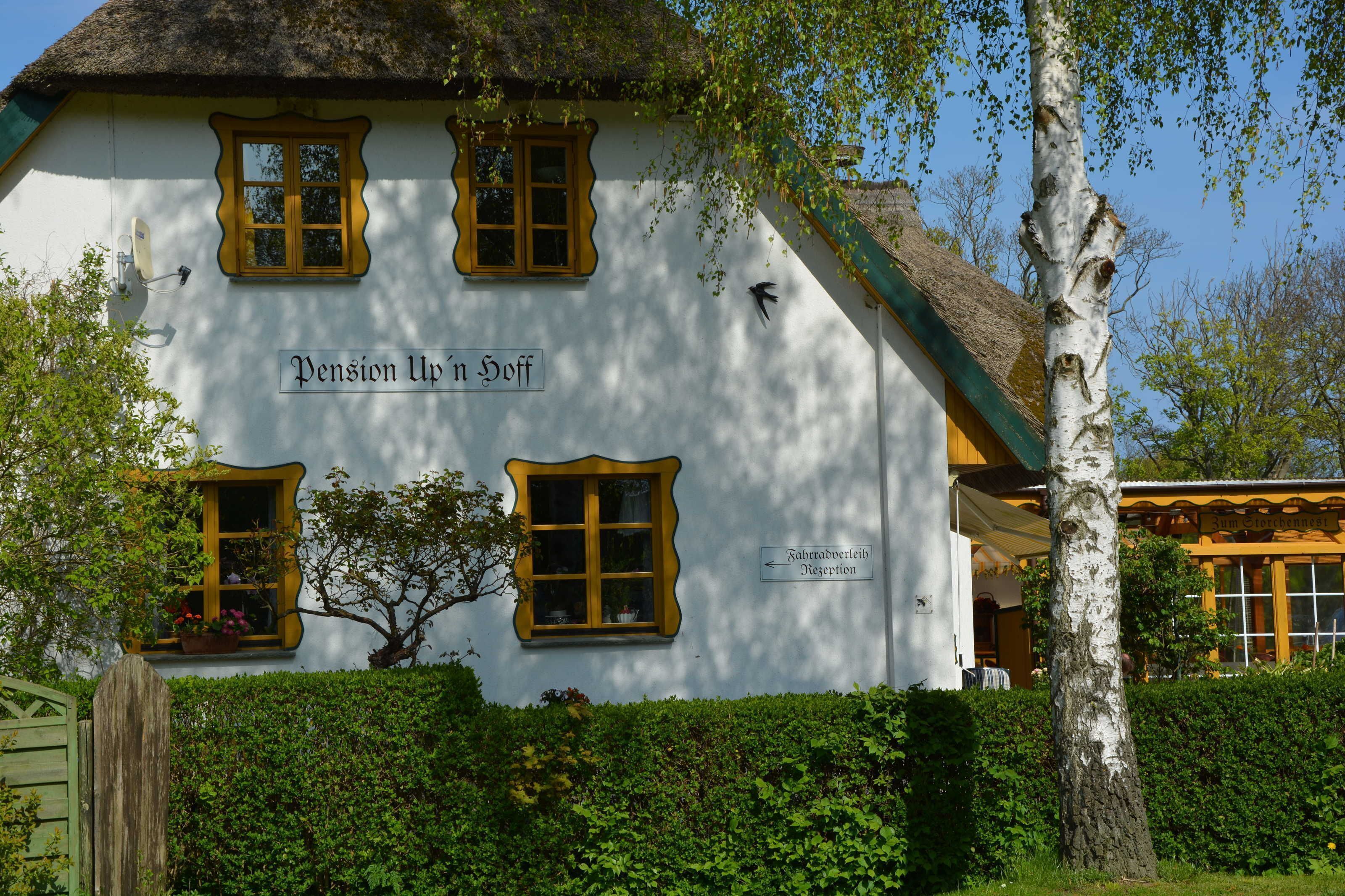 A white building with yellow window frames and a sign reading "Pension Uphn Doff".