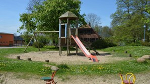 En legeplads med rutchebane, gynger og en klatrestruktur.