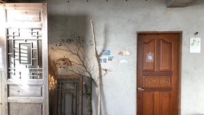 Une pièce avec une porte en bois, un banc et un paravent décoratif.
