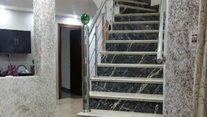 Una escalera de mármol con barandilla, que sube a un piso superior.