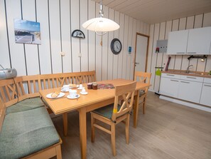 A dining area with a wooden table and chairs, a clock, and a radio on the wall.