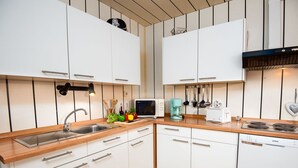 A modern kitchen with white cabinets, a wooden countertop, a sink, a stove, and various kitchen appliances. - Backbord by Interhome (Norddeich)
