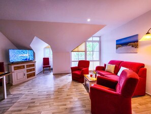 Un salon moderne avec un canapé rouge, un téléviseur et un meuble en bois.