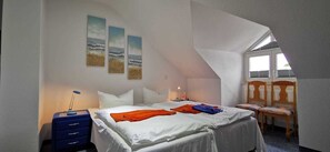 Un dormitorio con cama, escritorio, silla y ventana.