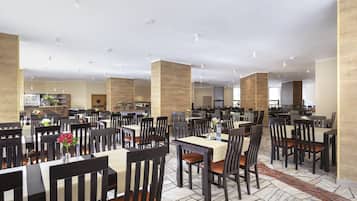 Un comedor amplio con varias mesas y sillas, techos altos y un diseño moderno y limpio.
