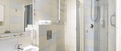 A modern bathroom with a glass-enclosed shower, a white sink, and a towel rack.