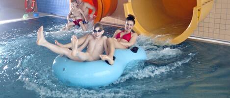 A water slide with large orange and yellow tubes, a pool, and a lifebuoy.