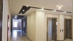 A hotel corridor with a modern design, featuring a marble floor, a ceiling with recessed lighting, and two elevators. - Apartment Osipova 40-9. (Odesa)