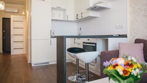A modern kitchen with white cabinets, a black countertop, and a stainless steel bar stool. - Apartment Osipova 40-9. (Odesa)