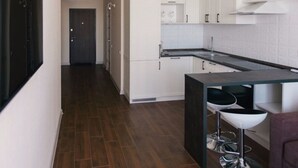 A modern kitchen with white cabinets, a dark countertop, and two bar stools. - Apartment Osipova 40-9. (Odesa)