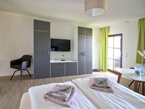 A hotel room with a bed, a desk, a chair, a TV, and a wardrobe.