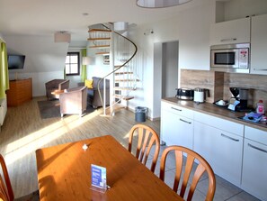 A modern kitchen with a microwave, coffee maker, and a dining area with a wooden table and chairs. - 2-room apartment / No. 35 - 3*** Appartementhotel Mare Balticum GmbH & Co KG (Sagard)