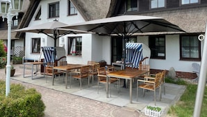 A building with a thatched roof and a patio area with wooden tables and chairs.