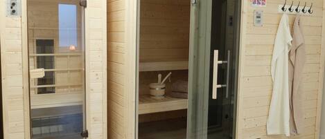 Un espai de sauna amb parets de fusta, una porta de vidre i un suport per a tovalloles.