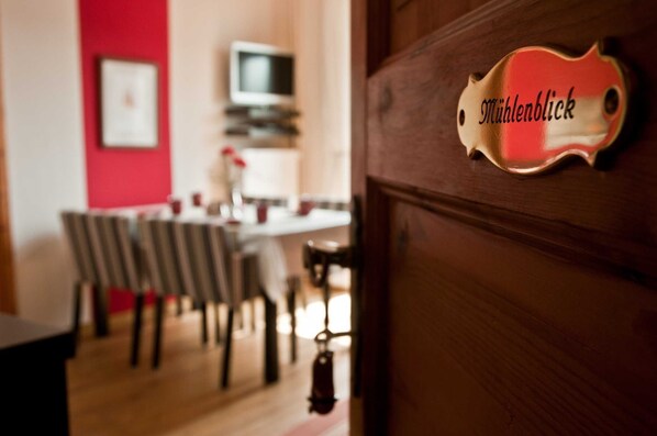 A room with a dining area, a television, and a door with a nameplate.
