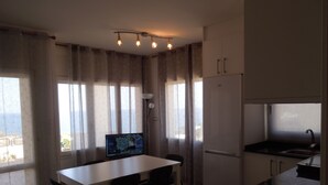 Een moderne keuken met een eethoek, grote ramen en een flatscreen televisie.