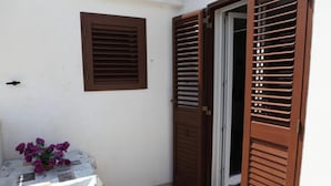 A small room with a table, a chair, and a door with wooden shutters. - Happy House on two levels (Ragusa)