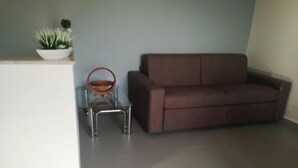 A room with a brown sofa, a small table with a potted plant, and a metal chair. - Happy House on two levels (Ragusa)