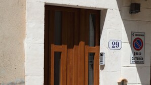 A wooden door with a glass panel, a number '29' sign, and a 'passo carrabile' sign on a building facade. - Happy House on two levels (Ragusa)