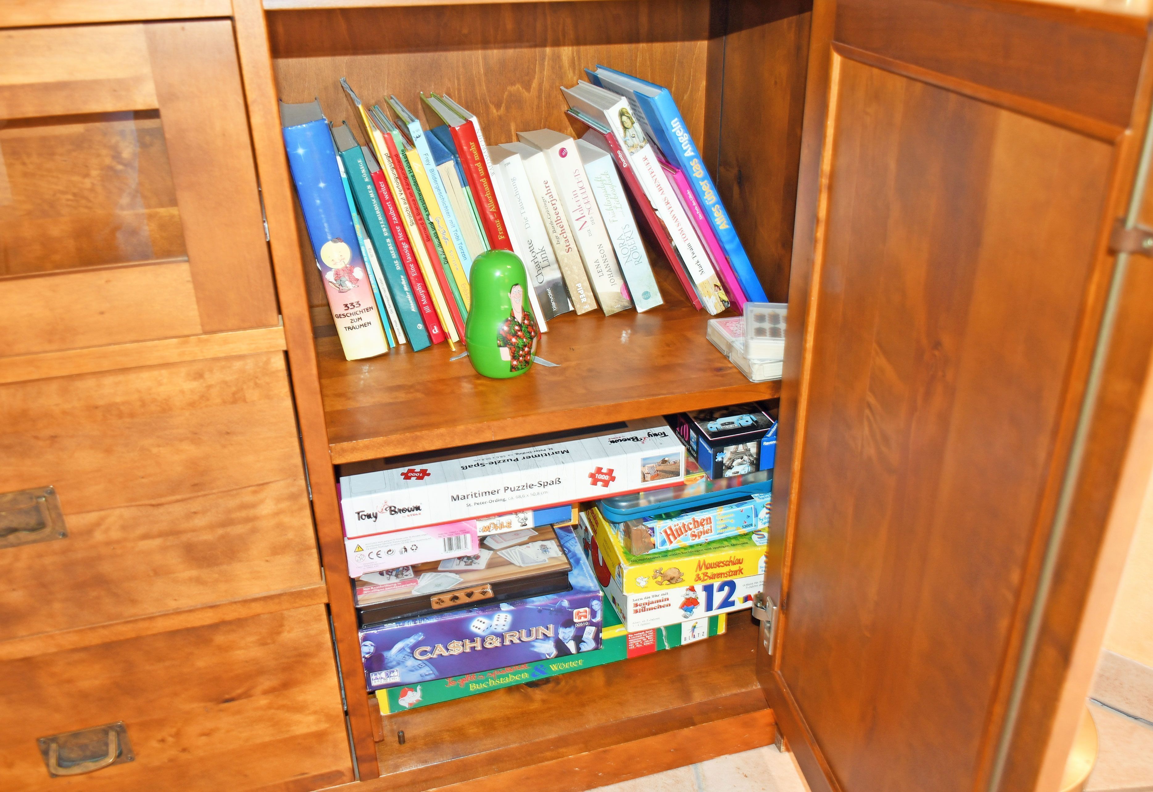 Un meuble en bois contenant des livres et des jeux de société.