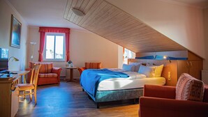 Een slaapkamer met een schuine kap, een bed, een bureau en een stoel.