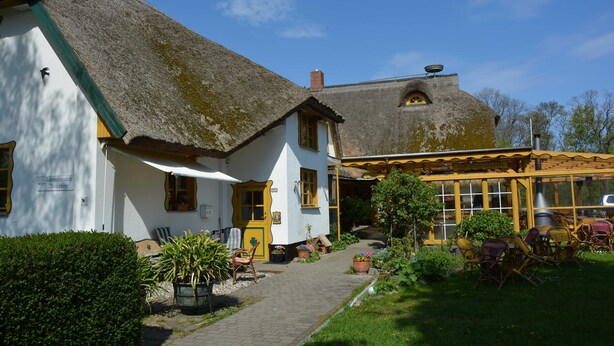 A traditional building with a thatched roof, a covered outdoor seating area, and a pathway leading to the entrance. - 7 - "Up'n Hoff", Germany (Middelhagen)
