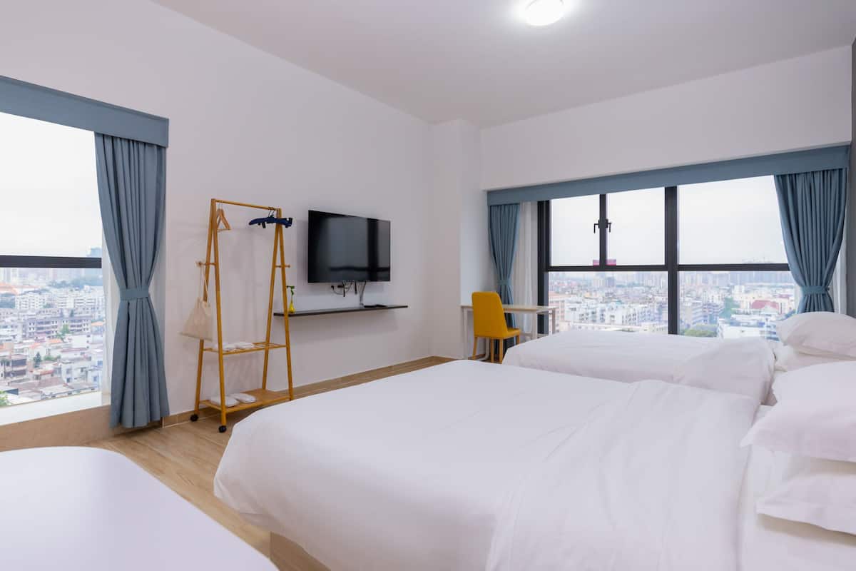 A hotel room with two beds, a TV, a desk, and a chair.