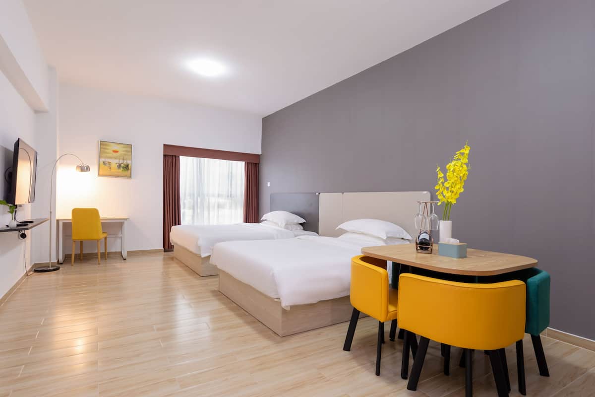 A hotel room with a bed, a desk, and a dining table with chairs.