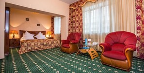 A hotel room with a large bed, two armchairs, a small table, and a patterned carpet. - Hotel Saya (Almaty)