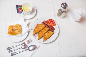 A table with a plate of food, a cup of tea, salt and pepper shakers, and a packet of tea. - Hotel Saya (Almaty)