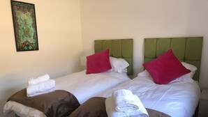 Two twin beds with green headboards, white bedding, and red pillows. - Fabulous Apartment in the City of Ripon, close to Cathedral with private parking (Ripon)